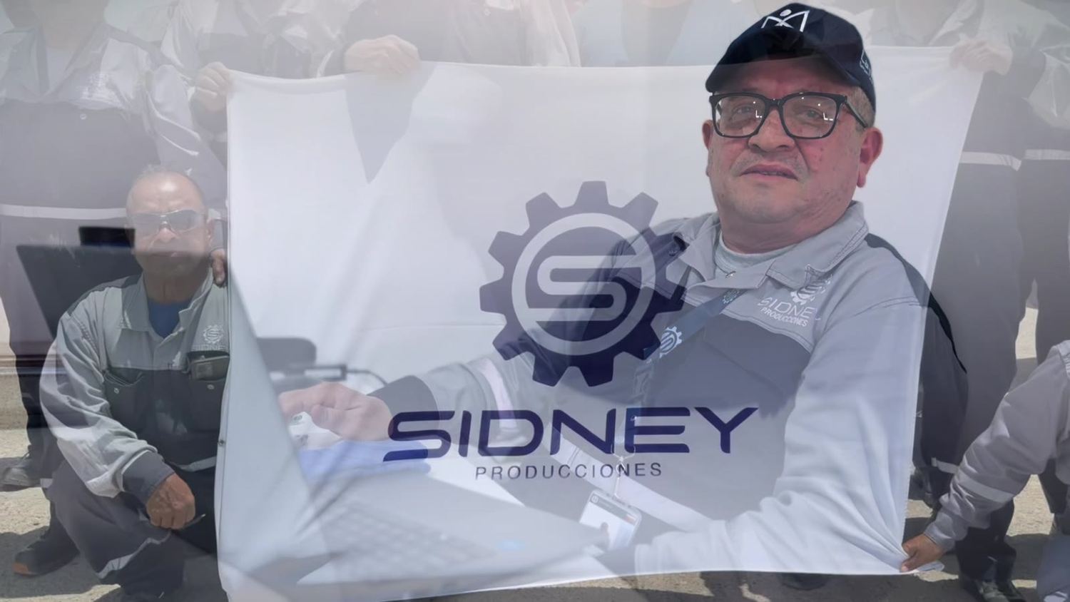 Personal de Sidney Producciones con la bandera de la empresa frente a la flota, en el Complejo Refinador Paraguaná